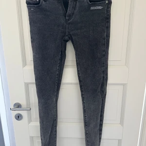 Grå skinny jeans från Off-White - Snygga grå jeans från Off-White med skinny passform och klassisk femficksdesign. Jeansen har dragkedjegylf och är tillverkade i denim med en tvättad look. Perfekta för dig som gillar streetwear och vill ha något stilrent men ändå edgy.