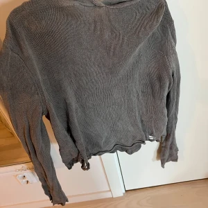 Grå stickad hoodie med lös passform - Grå stickad hoodie med lång ärm och lös passform. Tröjan har en stor huva och är tillverkad i ett mjukt stickat material. Perfekt för en avslappnad stil och enkel att matcha med jeans eller leggings.