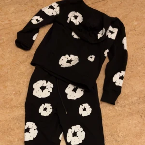 Svart hoodie med vita mönster - Cool svart hoodie med vita, abstrakta mönster. Tröjan har huva och långa ärmar, perfekt för en avslappnad stil. Matchande byxor ingår ej. Passar dig som gillar streetwear och unika prints.