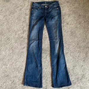 Lågmidjade bootcut jeans från 7 for all mankind - Säljer dessa lågmidjade bootcut jeans från 7 for all mankind. De är slitna baktill vid båda hälarna. Annars fint skick. Skulle säga att längden är 32-34 något men osäker. 