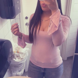 Ljusrosa topp med utsvängda ärmar - Säljer en ljusrosa topp med långa utsvängda ärmar och v-ringning. Toppen är tight och har en mjuk, stretchig känsla. Perfekt att styla med jeans eller kjol för en trendig look.