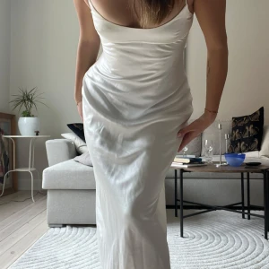 Lång satinklänning - Lång satinklänning från Zara 🤩 Så snygg, men kommer tyvärr inte till användning. Slits vid benen och ett spänne i ryggen som man kan välja att spänna för mer support, eller stoppa undan för att få bar rygg. Storlek M och är true to size. Nyskick förutom några gröna ränder som blivit på snöret pga metallspännena som färgat av sig, men inget som syns när man har på sig klänningen.