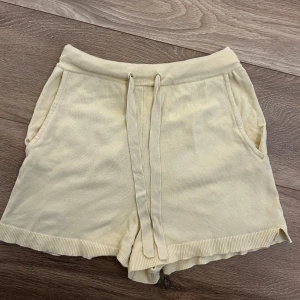 Stickade shorts - Mysiga stickade shorts i en ljusgul/beige färg med bred resår i midjan och snörning framtill. Shortsen har två sidofickor och ribbade kanter nertill. 