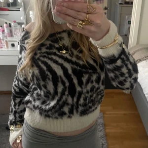 Zebramönstrad stickad tröja - Säljer en fluffig stickad tröja med zebramönster i svart och vitt. Modellen är croppad
