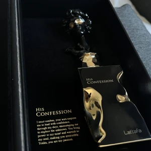 His Confession Eau de Parfum från Lattafa - Lyxig parfymflaska i svart med gulddetaljer och en unik skulptural design. Doften kommer i en elegant svart förpackning med guldtext. Blindbuy, inte min stil. Sprejat endast 6 gånger.
