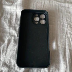 Svart mobilskal till iPhone 16 Pro Max - Säljer ett stilrent svart mobilskal med öppningar för kamera och knappar. Skalet är enkelt och passar perfekt för dig som vill ha ett diskret skydd till din mobil.