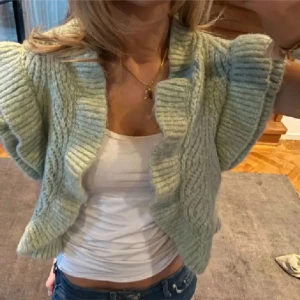 Stickad väst från Zara i ljusgrön - Superfin stickad väst från Zara i en ljusgrön nyans. Västen har korta ärmar, bred ribbad kant och en öppen front. Perfekt att slänga över en topp för en trendig lager-på-lager-look.