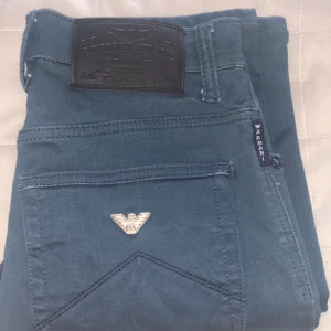 Blå jeansbyxor från Armani Jeans - Snygga blå jeansbyxor från Armani Jeans med klassisk femficksdesign och silverfärgad logga på bakfickan. Byxorna har normal passform och raka ben. Perfekta för dig som gillar stilrena och tidlösa plagg. Slim fit 