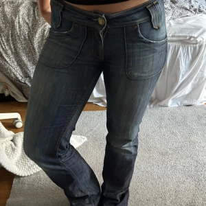 Lågmidjade jeans från Lee - Säljer ett par mörkblå jeansbyxor från Lee.  Byxorna har låg midja och är bootcut. Det är en av knapparna där bak som har lossnat och de är slitna vid hälarna. Det är också en lagning mellan benen men den syns inte så mycket pga att det är samma färg. Skriv gärna om du vill se bild på defekterna, kunde inte lägga in fler bilder. För referens är jag 160 cm och har ca 80 i midjemått