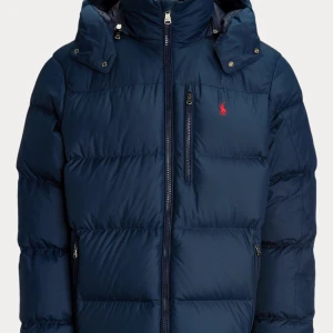 Mörkblå dunjacka från Polo Ralph Lauren - Säljer en mörkblå dunjacka från Polo Ralph Lauren med huva och dragkedja. Jackan har en röd broderad logga på bröstet och flera praktiska fickor med dragkedja. Knappt använd. Köpt för 5795kr. I färgen collection navy. 