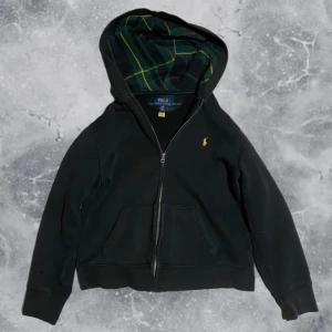 Ralph Lauren zip hoodie svart - •Ralph Lauren Full Zip Hoodie med rutig luva. Skick: 6-7/10, två små skador på höger sida av plagget, ej märkvärdigt(se bild) Storlek: 14/16 yrs= sitter som strl 160 cm. •Mått | axel neråt: 51,5 cm. Bredd: 43 cm. Modell: 173 cm, 63 kg drygt(sitter för litet på bild) Authentic: ✅ Mvh Hessler’s