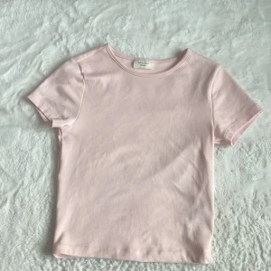 Ljusrosa t-shirt från Gina Tricot - En enkel och stilren ljusrosa t-shirt från Gina Tricot, Basically Basics-kollektionen. T-shirten har rund halsringning och korta ärmar. Perfekt basplagg i mjuk bomull som passar till allt.