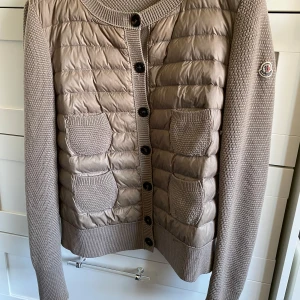 Cardigan jacka från Moncler - Säljer denna  populära och eftertraktade beige/bruna cardiganen från Moncler med stickade ärmar och quiltad framsida.  Självklart äkta och autenticiteten finns bekräftad på monclers hemsida. Skriv vid frågor och intresse, snabb leverans🙌🌟