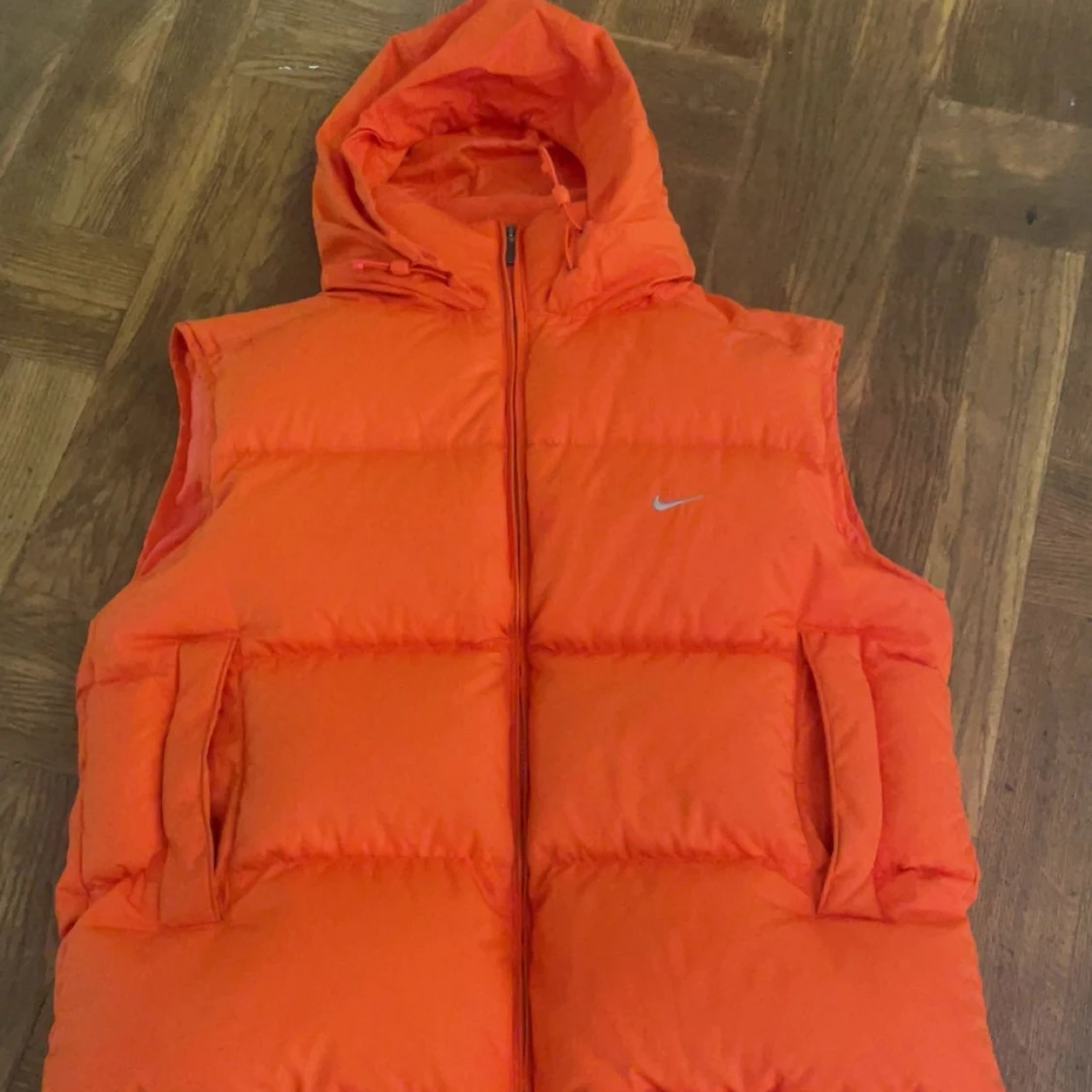 Orange dunväst från Nike med huva
