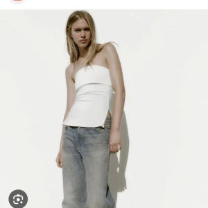 Vit axelbandslös topp - Säljer en stilren vit axelbandslös topp med figurnära passform. Toppen har en enkel och modern design som passar perfekt till jeans eller kjol. Perfekt för varma dagar eller när du vill ha en minimalistisk look.