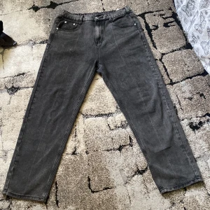 Grå jeansbyxor med rak passform - Säljer ett par grå jeansbyxor med normal passform och raka ben. Byxorna har klassiska fem fickor, resår i midjan baktill och stängs med dragkedja och knapp. Inte använt så mycket 