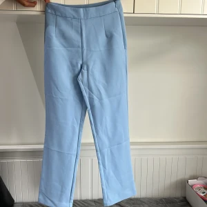 Ljusblå kostymbyxor från Bik Bok - Snygga ljusblå kostymbyxor från Bik Bok med raka ben och hög midja. Byxorna har diskreta fickor fram och en enkel passform som ger en clean look. Perfekta att styla med en enkel topp eller kavaj.