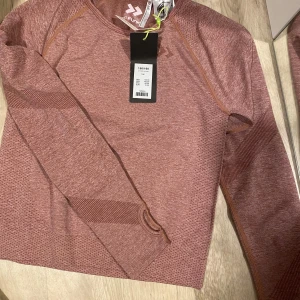 Rosa långärmad träningströja från 157 Funk - Säljer en rosa långärmad träningströja från 157 Funk med Quickdry-teknologi. Tröjan har diskreta mönsterdetaljer på ärmar och kropp samt rund halsringning. Perfekt för träning och sportaktiviteter.