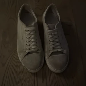 Beiga sneakers från Axel Arigato - Säljer ett par stilrena beiga sneakers från Axel Arigato med klassisk design och rund tå. Skorna har snörning och platt sula, perfekta för en clean och modern look. Passar till det mesta och är riktigt snygga till jeans eller chinos. Skorna är lite skitiga men jag kan tvätta dem innan de skickas! Pris kan diskuteras. Enligt skorna hänger med.