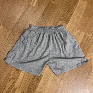 Grå shorts med resårmidja - Gråa shorts i mjukt material med elastisk midja och avslappnad passform. Perfekta för varma dagar eller som chillplagg hemma. Klassisk design utan synliga detaljer eller mönster.