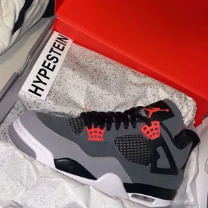 Nike Air Jordans i grått och rött - Säljer ett par Nike Air Jordans med grå ovandel, svarta och röda detaljer samt vit sula. Skorna har klassisk meshpanel på sidan, svarta skosnören och Jumpman-logga på plösen. Perfekta för dig som gillar streetwear och sneakerskultur.