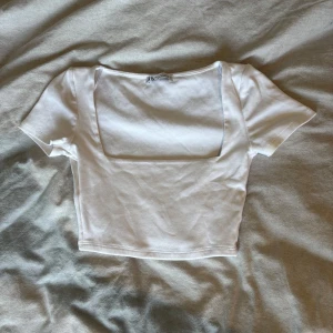 Vit croppad topp med fyrkantig ringning - Säljer en vit croppad topp från Zara med korta ärmar och fyrkantig ringning. Perfekt till jeans eller kjol! 