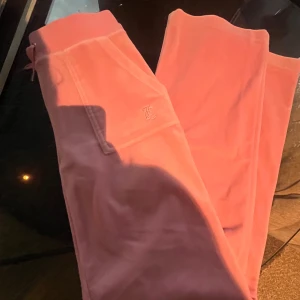 Rosa Juicy Couture byxor - Säljer ett par klassiska rosa mjukisbyxor från Juicy Couture i supermjuk bomullsblandning. Byxorna har snörning i midjan, bakficka med tryckknappar och broderad logga fram. Har tappat en del på snör detaljen men det är inget man tänker på! Skicka gärna till mig vid vidare frågor😊🫶🩷