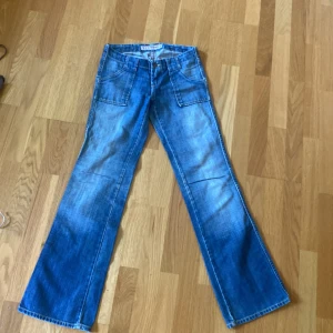 Bootcut blå jeans - Säljer ett par klassiska blå Lågmidjade bootcut jeansbyxor  och stora fickor fram och bak. Jeansen har en utsvängd passform och är tillverkade i denim. 