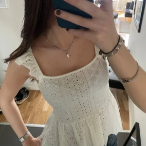 Vit broderad topp  - Säljer en söt vit topp med broderade detaljer och volang vid axlarna. 