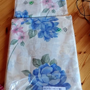 Gardinkappa med blommönster samt 5 meters bunt. - Säljer en vacker gardinkappa med blommönster i blått och rosa. Tyget har stora blommor och gröna blad mot en ljus bakgrund. Perfekt för att ge rummet en fräsch och färgglad känsla. Gardin samt gardintyg 5 meters bunt Lewis Flower Blue.,se bilder.
