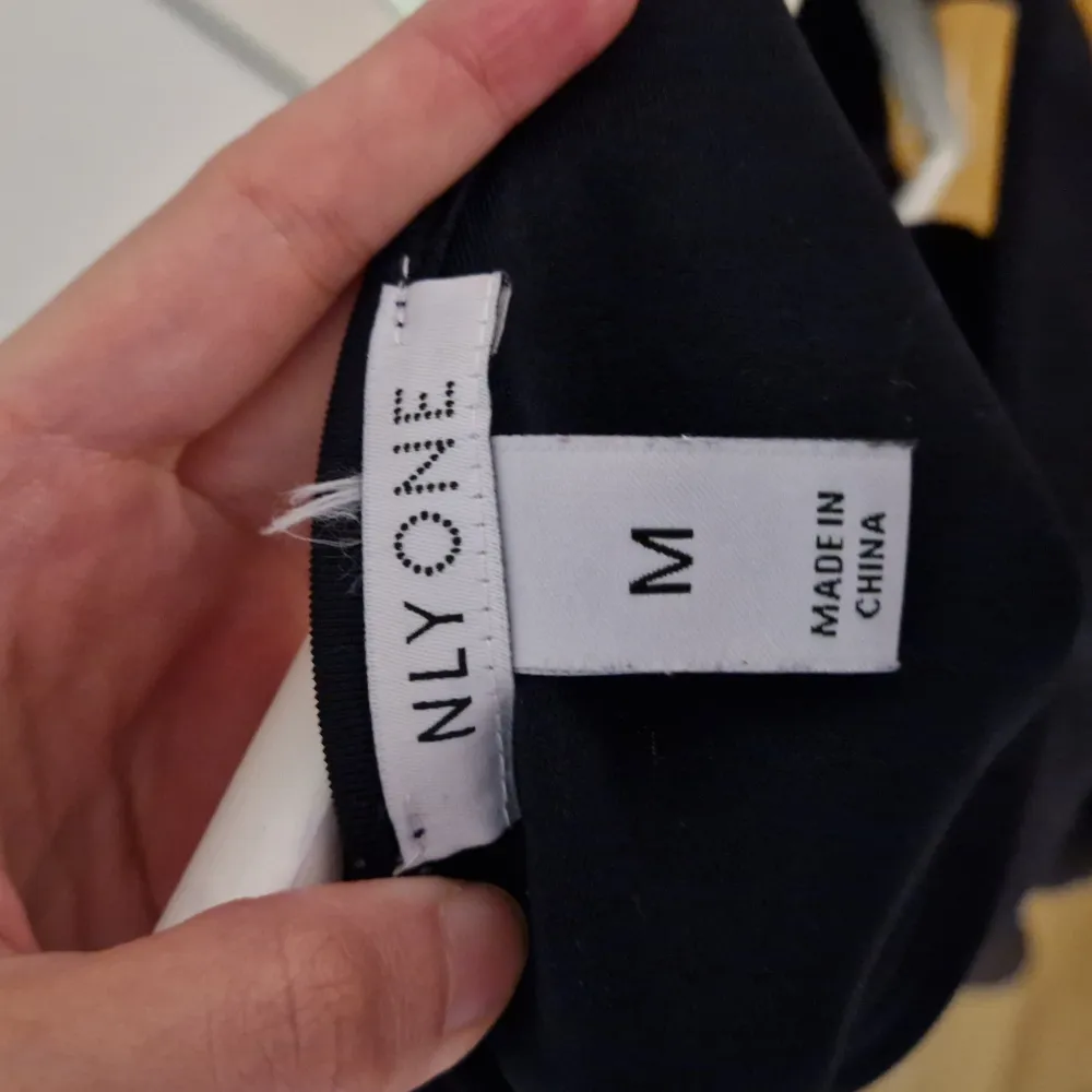 Elegant mörkblå klänning från NLY One med ärmlös design och veckad kjol. Klänningen har en stilren öppen ryggdetalj som ger en extra touch. Perfekt för en kväll ute eller en speciell tillställning.. Mekot.