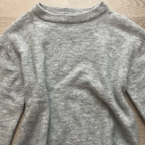 Grå stickad tröja 💘 - Mysig grå stickad tröja med ribbad krage och mjukt material. Perfekt för kyliga dagar och enkel att matcha med olika outfits. Ett måste i garderoben för en stilren look.