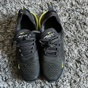 Svarta Nike Air Max med gula detaljer - Säljer ett par svarta Nike Air Max med snygga gula detaljer. Skorna har en luftig design med snörning och en synlig luftkudde i hälen för extra komfort. Perfekta för både träning och vardag.