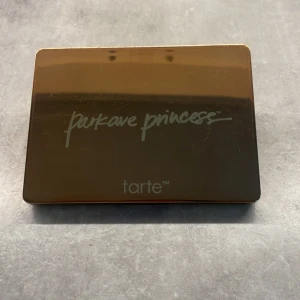 Park Ave Princess Contour Palette från Tarte - Snygg contour palette från Tarte med tre nyanser för att skapa en perfekt kontur. Paletten innehåller en matte bronzer, en matte blush och en skimrande highlighter, perfekt för att framhäva ansiktsdragen. Kompakt och elegant design i guld,karamell och matte rosa💗