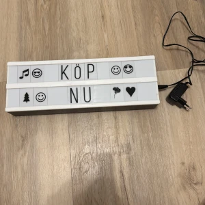 Ljusskylt med bokstäver och symboler - Säljer en ljusskylt med utbytbara bokstäver och symboler. Perfekt för att skapa personliga meddelanden. Skylten är vit med svart text och har en sladd för strömförsörjning. Inkluderar en mängd olika bokstäver och symboler för att anpassa ditt budskap.