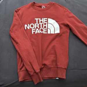 Röd North face tröja - Säljer en clean mörkröd tröja från North Face med logga på framsidan, Tröjan har långa ärmar perfekt för en laidback stil.