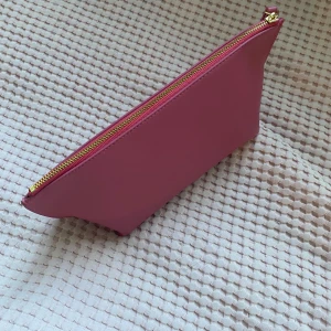 Rosa necessär från H&M - Säljer en stilren rosa necessär från H&M. Den har en praktisk dragkedja i guld och är perfekt för att förvara smink eller andra småsaker. Enkel och snygg design som passar i alla väskor.