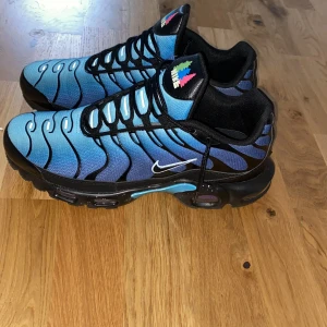 Nike Air Max Plus i blått och svart -  Varan är använd 5 gånger.Säljer ett par Nike Air Max Plus i en cool blå och svart färgkombination. Skorna har ett vågigt mönster och en synlig Air Max-dämpning i sulan. De har snörning och en liten Nike-logga på sidan. Perfekta för dig som vill ha en stilren och bekväm sneaker.