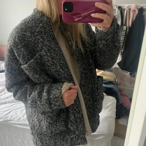 Carin Wester jacka - Säljer en mysig gråmelerad jacka med dragkedja framtill. Jackan har en avslappnad passform och stora fickor på sidorna. Perfekt för kyliga dagar.