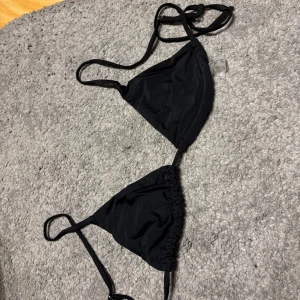 Svart bikini med knytband - Snygg svart bikini med justerbara knytband. Perfekt för stranden eller poolen. Enkel och stilren design som passar alla tillfällen. Strl S men väldigt liten