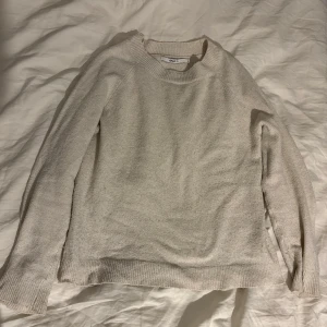 Beige stickad tröja från only - Säljer en stilren beige stickad tröja från only. Tröjan har en klassisk rund hals och långa ärmar med ribbade muddar. Perfekt för kyligare dagar och lätt att matcha med olika outfits.
