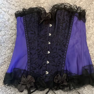 Lila och svart korsätt top - Svart och lilla korsätt top med snören där bak för att tajta.