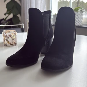 Svarta boots med klack från XIT - Snygga svarta boots i mocka med hög klack och rund tå. Insidan har ett leopardmönster som ger en cool kontrast. Perfekta för att lyfta vilken outfit som helst.