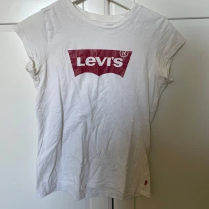 Vit t-shirt från Levi's - Säljer en klassisk vit t-shirt från Levi's med deras ikoniska röda logga på bröstet. Passar till allting och är en väldigt skön tröja❣️