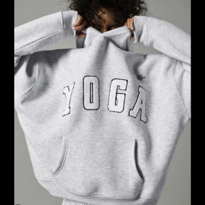Grå hoodie med texten YOGA - Säljer en grå hoodie med texten YOGA i stora bokstäver på framsidan. Tröjan har en klassisk känguruficka och en bekväm huva. Perfekt för en avslappnad stil eller för att mysa hemma.