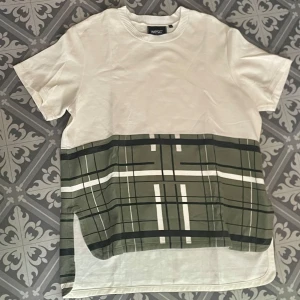 Vit och grön t-shirt från Wesc - Säljer en unik t-shirt från Wesc i storlek L. Den är vit med ett grönt rutigt mönster nedtill. Hör av dig vid intresse!