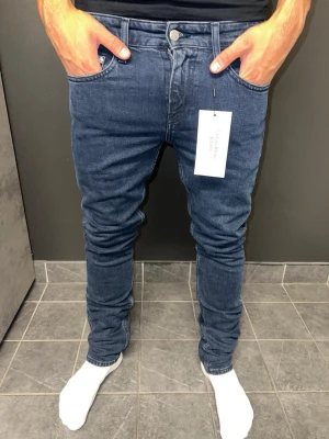 Calvin Klein Jenas  - Snygga mörkblå slim fit jeans med klassisk femficksdesign och normal midja. Jeansen har en smal passform hela vägen ner och är tillverkade i stretchigt denimtyg för extra komfort. Perfekta för en trendig och avslappnad look.