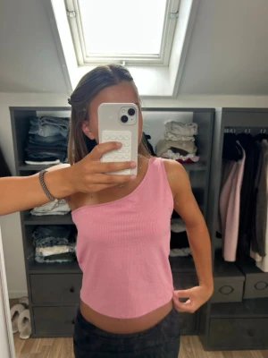 Rosa oneshoulder ribbad topp - Säljer en rosa ribbad topp med oneshoulder-design. Toppen är croppad och har en snygg, enkel look som passar perfekt till jeans eller kjol. Materialet känns mjukt och stretchigt, vilket gör den bekväm att bära. Inte använd många gånger så mycket bra skick fortfarande. Kom privat om du vill ha fler bilder i andra vinklar och pris kan diskuteras💗