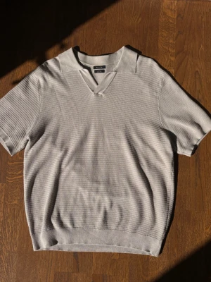 Beige Pikétröja från Massimo Dutti i nyskick - Stilren stickad piké i beigegrå ton från från Massimo Dutti. Tröjan har en öppen krage utan knappar och är tillverkad av 100% bomull med en struktursstickad textur.  Skick: Tröjan är endast provad hemma. Lappen är avtagen men medföljer. Inga anmärkningar, fläckar eller noppor. Säljes då den var något för stor för mig (bär vanligtvis medium).  Storlek: Large och passar true to size.   Nypris: 599kr  Har du undringar så hör av dig!    #MassimoDutti #piké #polo #stixkat #beige #grå #Oldmoney