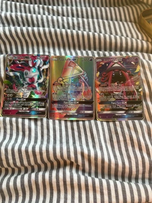 Pokémon GX samlarkort 3-pack - Tre Pokémon GX samlarkort: Sylveon GX, Tapu Lele GX och Tapu Fini GX. Korten har holografisk yta och färgstarka illustrationer i anime-stil. Tillverkade i laminerad papp, perfekta för dig som vill utöka din samling med unika och snygga kort.